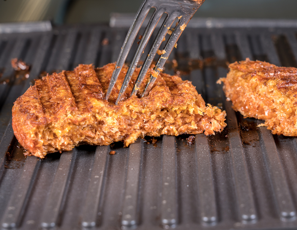Záber zblízka na mäsové karbonátky na rastlinnej báze pre vegetariánske hovädzie hamburgery, ktoré sa grilujú na horúcej panvici.